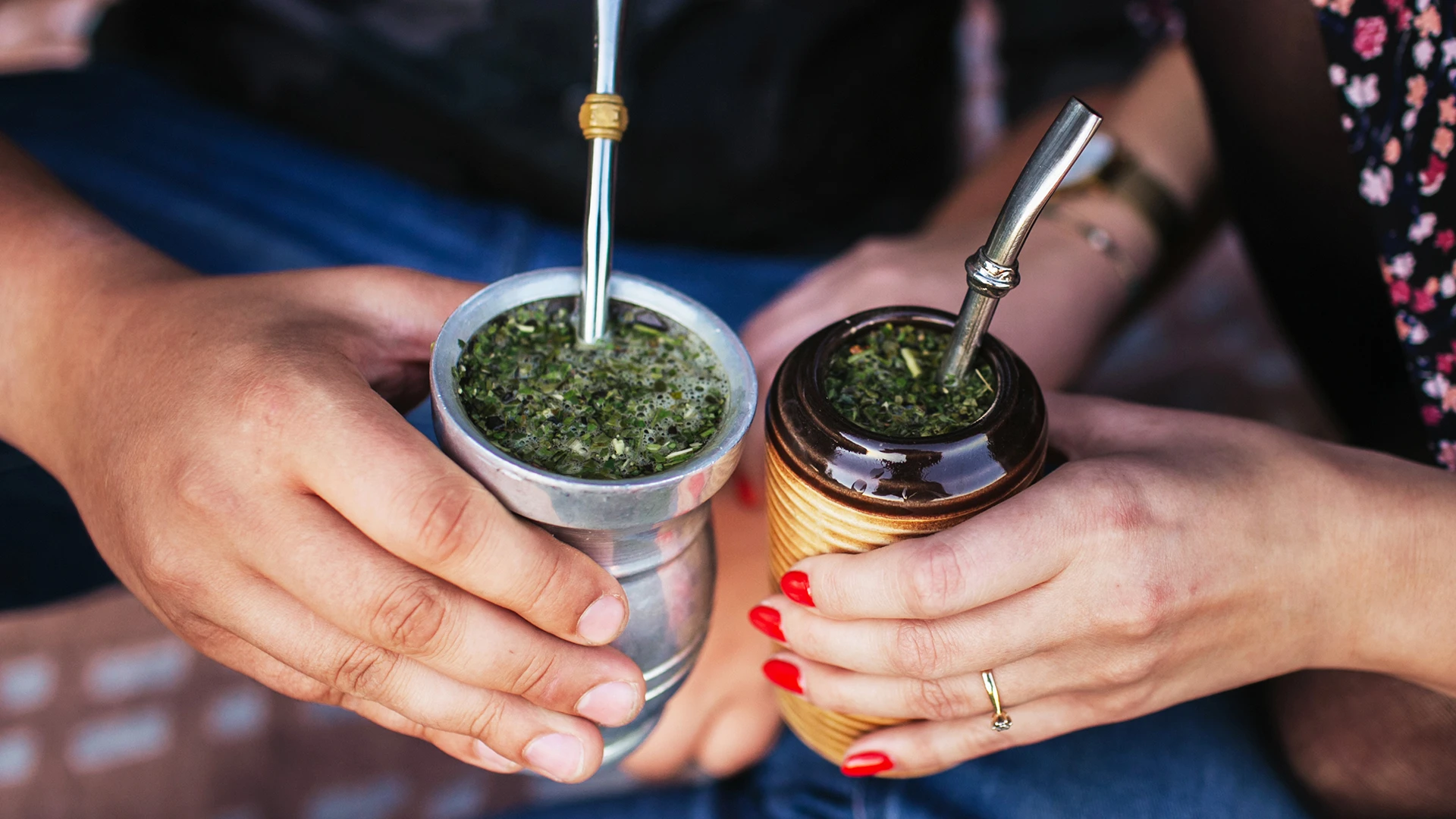 Image of two stylish people with authentic yerba mate cups and gourds and metal bombilla straws illustrating the yerba mate benefits.